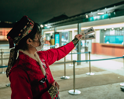 Pengunjung yang memakai hanbok sedang memegang tiket.